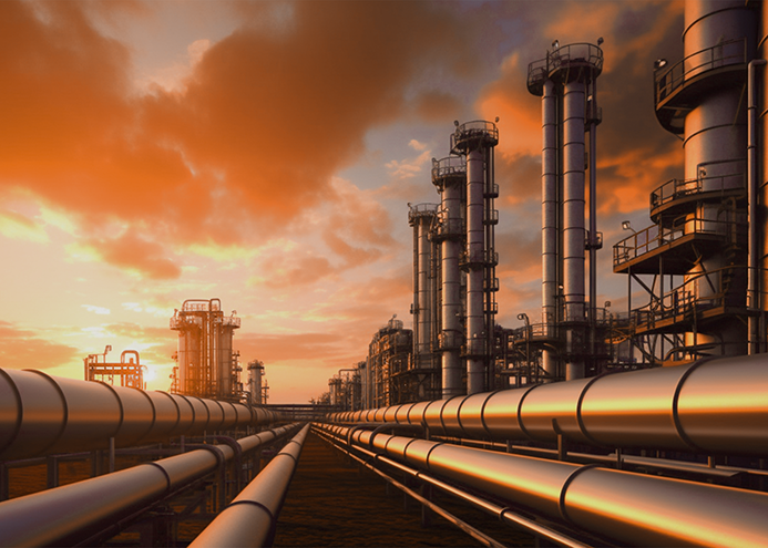 An oil company's industrial facility with distillation towers and pipelines at sunset